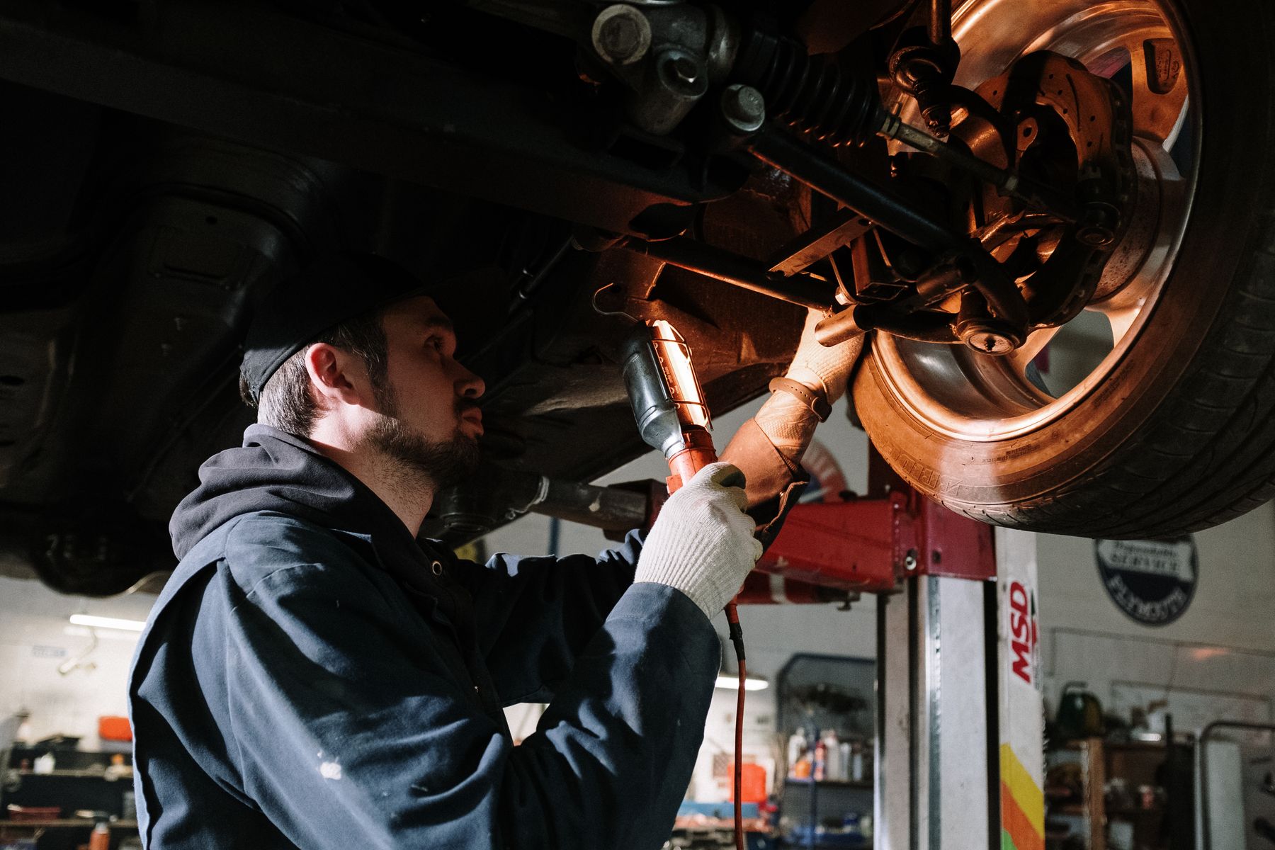 Mechanic inspecting a wheel, brakes and suspension on a lift during alignment work
