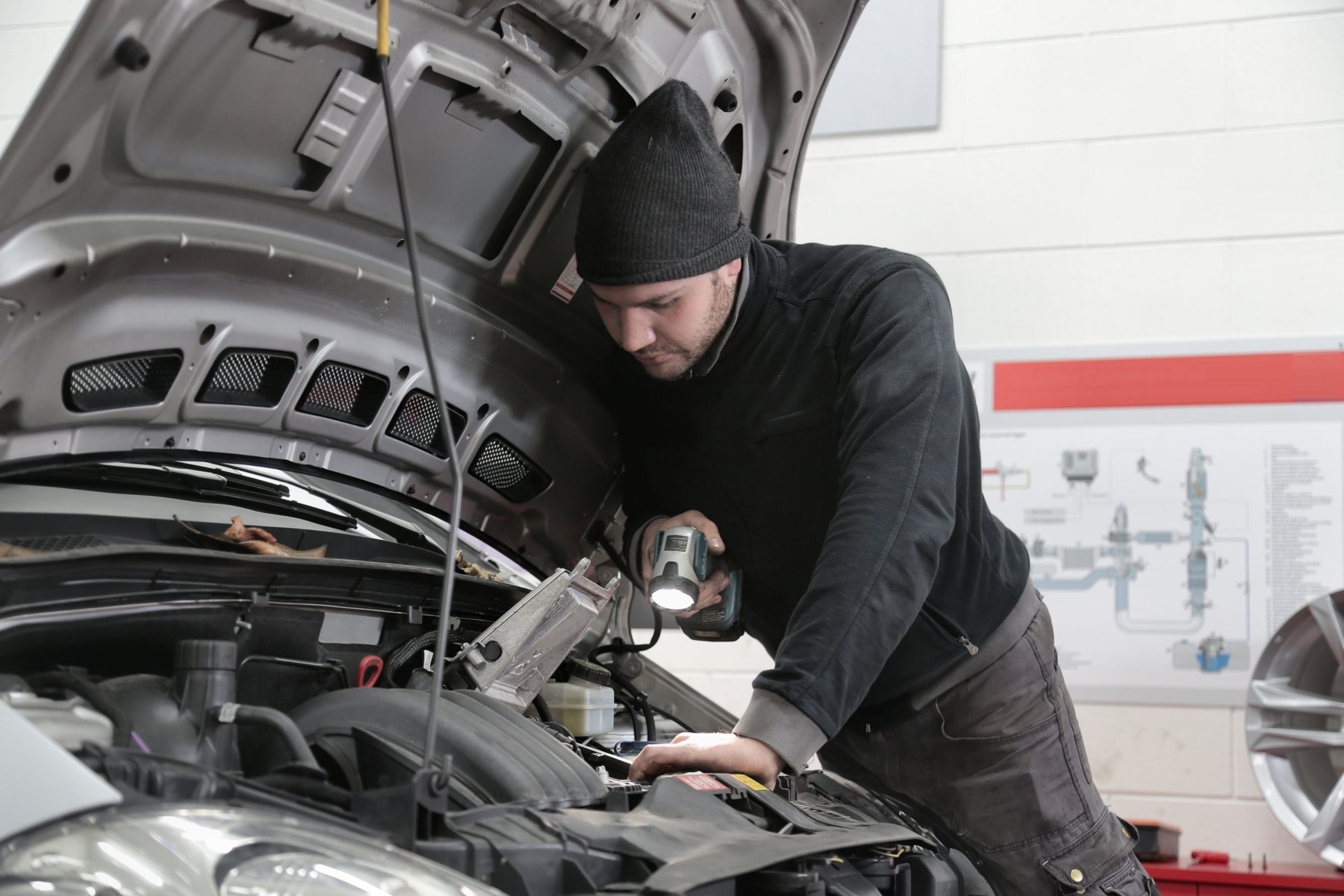 Technician inspecting a modern car engine bay with a work light in a Waterford workshop